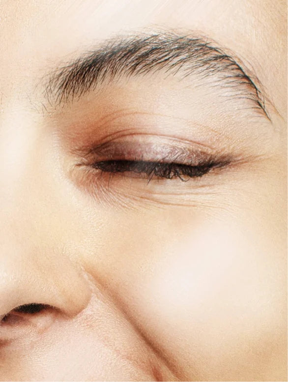 Close-up of a person's eye with makeup, focusing on the eyelid and eyebrow area.